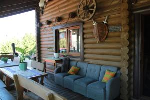 porche de una cabaña de madera con sofá y mesa en Pirtis ir nakvynė pajūrio regioniniame parke 