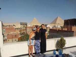 um grupo de pessoas em pé em um telhado com pirâmides no fundo em Eagles Pyramids View no Cairo