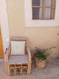 una sedia di vimini con cuscino seduta accanto a un edificio di Tanirt ecolodge a Siwa