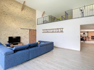 een woonkamer met een blauwe bank en een tv bij Au Vent des Collines in Les Épesses