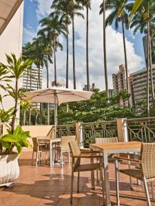 a patio with tables and chairs and palm trees at Hotel Cassino Tower Campinas Cambuí in Campinas
