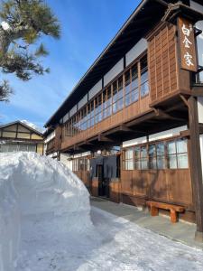 a building with a snow pile in front of it at 宿屋白金家 yadoya-shiroganeya 1日1組限定2名から8名様まで 全館貸切り 伝統的建造物の旅籠宿 Traditional culture experience in Nagano