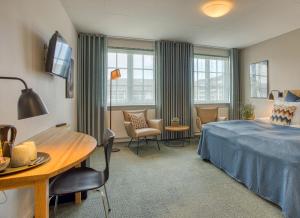 スケーエンにあるカラー ホテル スカーイェンのベッド、テーブル、椅子が備わるホテルルームです。