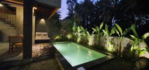 - une petite piscine dans un jardin la nuit dans l'établissement Purana Boutique Resort, à Ubud