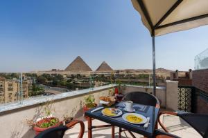 a table and chairs on a balcony with pyramids at Dream Inn in Cairo