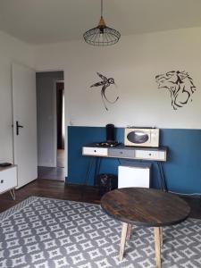 a living room with a table and a blue wall at Chambre Salon Sdb Jardin près Bordeaux in Cestas