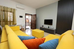 a living room with yellow and blue couches and a television at Berat Central Apartment in Berat