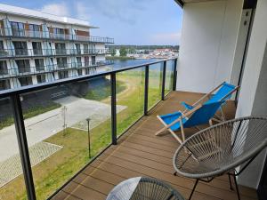 un balcón con una silla azul y vistas a un edificio en Apartament z Mewami - Dziwnów Bridge Apartaments & Spa en Dziwnów