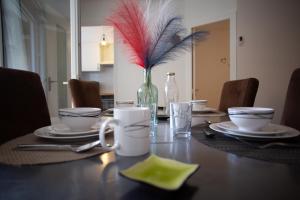 mesa de comedor con jarrón de plumas rojas en Le Cyprès - Charmant, Agréable et Tout Confort en Béziers