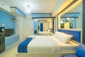 a bedroom with a large white bed and a tv at Studio at Bassura City East Jakarta Netflix in Jakarta