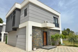 アンタルヤにあるVilla Kemer Kutluのグレーと白のファサードを持つ現代的な家