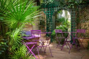 un grupo de sillas y mesas púrpuras en un jardín en Hôtel Galileo Champs Elysées, en París