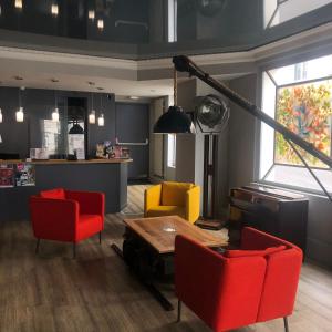 ein Wohnzimmer mit roten und gelben Stühlen und einem Tisch in der Unterkunft Cit'Hotel Europeen in Angoulême