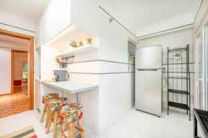- une cuisine avec des murs blancs, un réfrigérateur et des tabourets dans l'établissement GuestReady - A Cosy Retreat in Lumiar, à Lisbonne