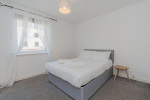 een witte slaapkamer met een bed en een raam bij GuestReady - Restful stay near Edinburgh Castle in Edinburgh