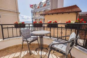 una mesa y sillas en un balcón con flores en AMMOTTI Hotel and Apartments, en Ohrid