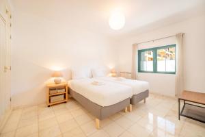 een witte slaapkamer met een bed en een raam bij GuestReady - Relaxation near Carcavelos Beach in Carcavelos