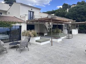 een huis met een patio met stoelen en een parasol bij Villa Les Issambres, 8 pièces, 14 personnes - FR-1-768-62 in Les Issambres