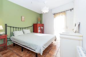 1 dormitorio con cama blanca y paredes verdes en Cozy stay in Pobla Farnals - 15 min from Valencia, en La Pobla de Farnals