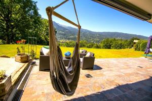 a hammock on a patio with a couch and mountains at Stylish place-Amazing Views-3 main lifts, Apt design- vue splendide-3 Telecabines in Samoëns