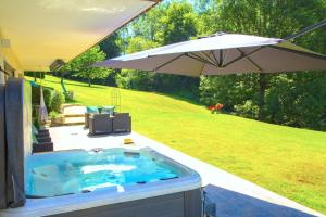 a hot tub in a yard with an umbrella at Stylish place-Amazing Views-3 main lifts, Apt design- vue splendide-3 Telecabines in Samoëns