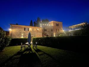 a table and chairs in front of a building at night at Fattoria Di Pancole in San Gimignano