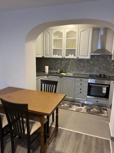 a kitchen with white cabinets and a wooden table at Pavković Apartmani in Posušje