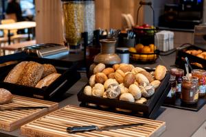 a table topped with trays of different types of bread at Zleep Hotel Zürich-Kloten in Kloten