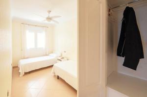 a white bedroom with two beds and a window at Summerlandrota La Caleta in Rota