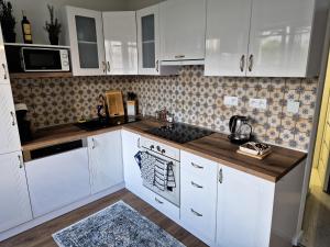 a kitchen with white cabinets and a stove top oven at Apartmán Lesa Brezno in Brezno +18 photos