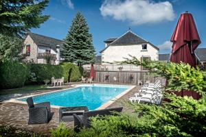 a swimming pool with chairs and a house at Hotel Le Rocher Blanc in Albaret-Sainte-Marie