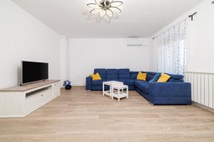 a living room with a blue couch and a tv at Apartman Mediteran in Crikvenica