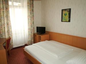 um pequeno quarto com uma cama e uma televisão em Hotel Terminus em Viena