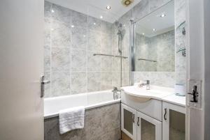 Baño blanco con bañera y lavamanos en GuestReady - Uma escapadela encantadora em Londres, en Londres