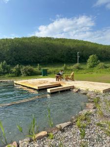 a person sitting on a picnic table on a dock over water at Wrth y Nant in Saint Ishmael