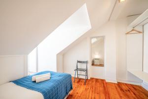 um quarto branco com uma cama azul e uma cadeira em GuestReady - B-MAD Museum At Your Doorstep em Lisboa