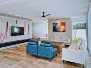 sala de estar con sillas azules y TV en VILLA LUXURY 5PN SANCTUARY RESORT - TRUNG TÂM HỒ TRÀM l gần biển CÁCH 20MET, en Xuyên Mộc