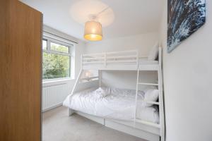um quarto com um beliche branco e uma janela em GuestReady - Tranquil Retreat near Bramall Hall em Cheadle