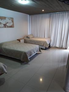Duas camas num quarto com pisos em azulejo branco em Lujan Homes em Luján