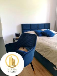 Un dormitorio con una silla azul junto a una cama en Apartament Granatowy, en Tychy