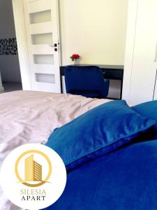 uma cama com um edredão azul e uma placa em Apartament Granatowy em Tychy