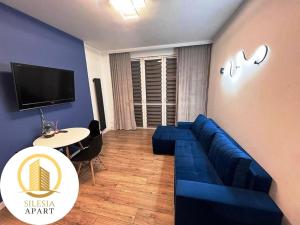 a living room with a blue couch and a table at Apartament Granatowy in Tychy