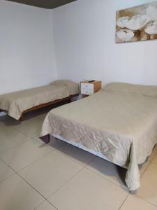 Duas camas num quarto com piso branco em Lujan Homes em Luján