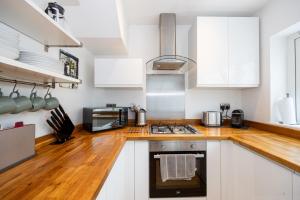 a kitchen with white cabinets and a wooden counter top at GuestReady - Tranquil Retreat near Bramall Hall in Cheadle