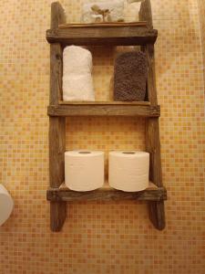 una mensola in legno con tre rotoli di carta igienica su un muro di La Serra Sognante Guest house con giardino a Firenze