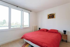 um quarto com uma cama vermelha e 2 janelas em GuestReady - Calm and Charm near Bois de Boulogne em Saint-Cloud