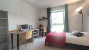 a bedroom with a bed and a desk with a computer at Neoresid - Résidence du Parc in Reims