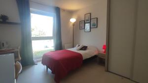 a bedroom with a bed with a red blanket and a window at Neoresid - Résidence du Parc in Reims