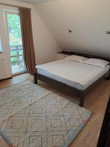 Schlafzimmer mit einem Bett mit einem Teppich und einem Fenster in der Unterkunft Pension Casa Contelui in Râșnov