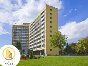 a yellow building in front of a green field at Apartament Granatowy in Tychy